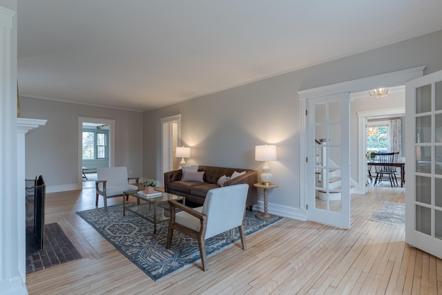living area featuring baseboards, a healthy amount of sunlight, crown molding, and hardwood / wood-style flooring