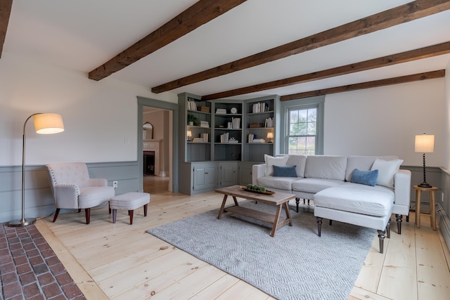 living area with a fireplace, wood finished floors, and beam ceiling
