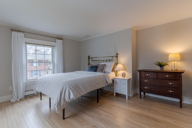 bedroom with light wood finished floors, crown molding, baseboards, and a baseboard heating unit