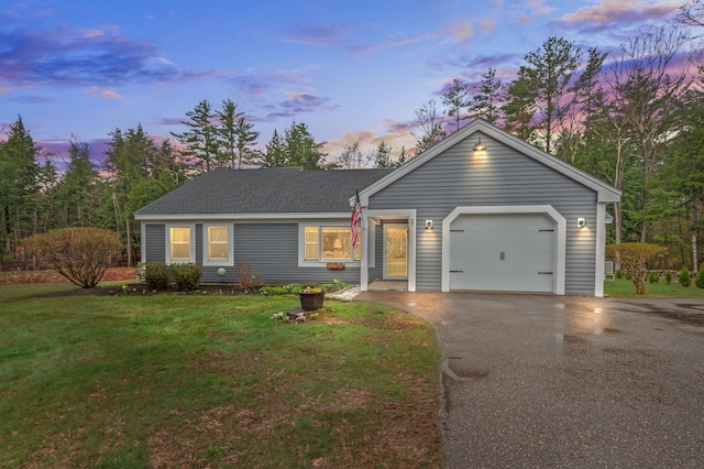 ranch-style house featuring an attached garage, a front lawn, and driveway
