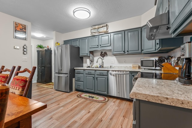 kitchen with light wood-type flooring, light countertops, appliances with stainless steel finishes, and a sink