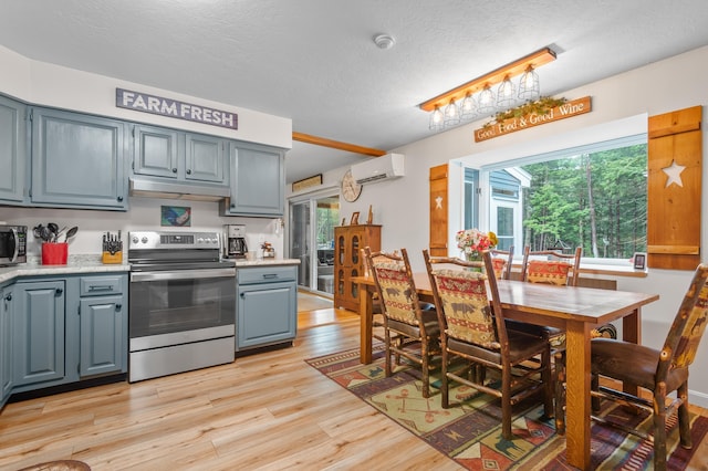 kitchen with under cabinet range hood, a healthy amount of sunlight, stainless steel appliances, and a wall unit AC