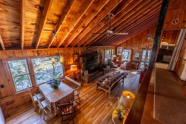 living area featuring wooden walls, vaulted ceiling with beams, plenty of natural light, and wood finished floors