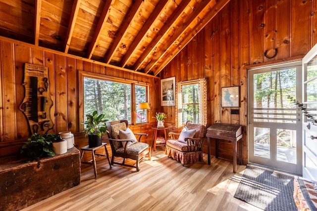 living area with lofted ceiling with beams, wood walls, light wood-style flooring, and wood ceiling