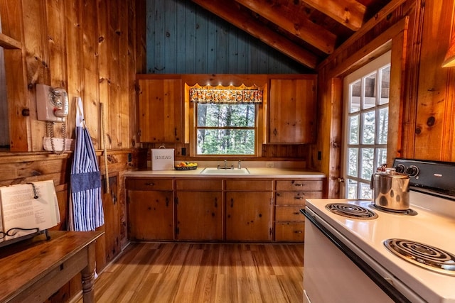 kitchen with brown cabinetry, wood walls, light countertops, range with electric cooktop, and light wood-style floors