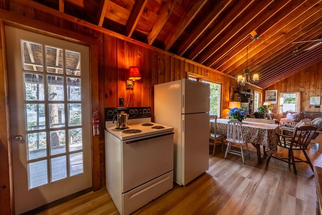 kitchen featuring lofted ceiling, white appliances, wooden walls, a chandelier, and light wood-type flooring