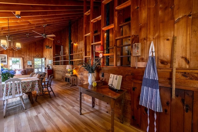 interior space with high vaulted ceiling, wood walls, ceiling fan, and wood finished floors