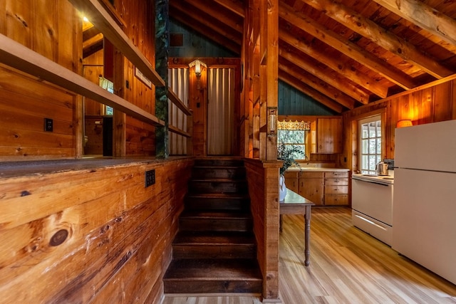 stairway featuring wood walls, wood finished floors, and vaulted ceiling with beams
