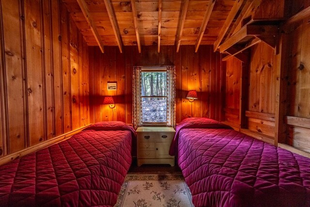 bedroom with wood walls, wood ceiling, and beamed ceiling