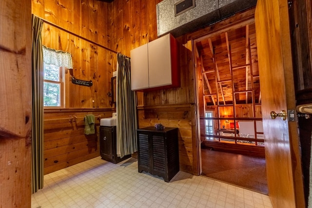 bathroom with wooden walls, visible vents, and tile patterned floors