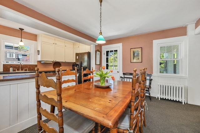 dining room with plenty of natural light, dark carpet, and radiator heating unit