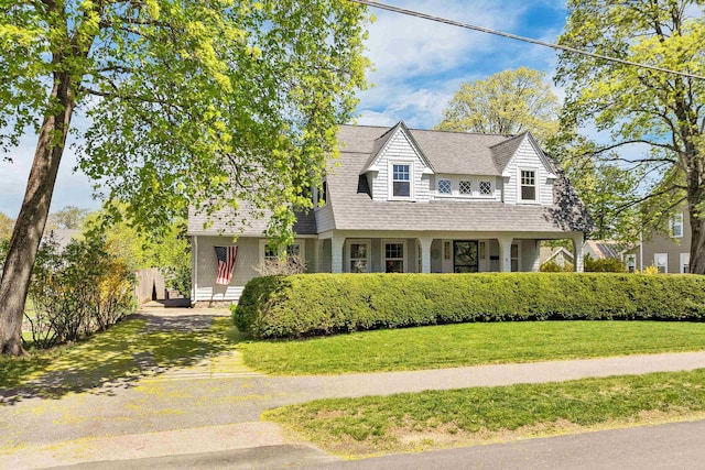 cape cod-style house with a porch, roof with shingles, fence, driveway, and a front lawn