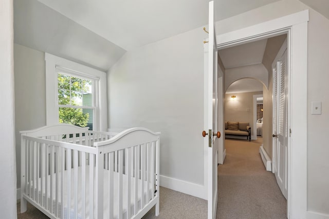 bedroom with lofted ceiling, a baseboard heating unit, carpet, arched walkways, and baseboards