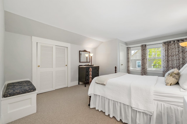 bedroom featuring lofted ceiling, light carpet, and a closet