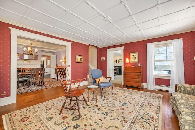 living room with a notable chandelier, baseboard heating, wallpapered walls, hardwood / wood-style flooring, and arched walkways