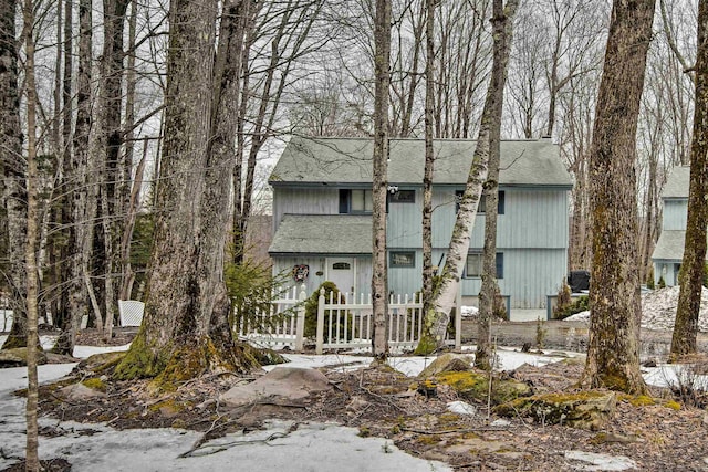 view of snowy exterior featuring a shingled roof and fence private yard