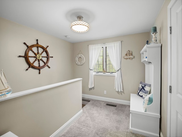 hall featuring an upstairs landing, visible vents, baseboards, and carpet floors