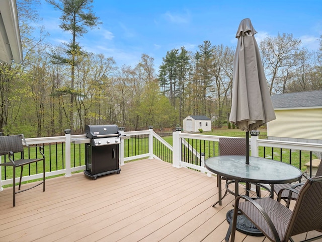 wooden terrace with a lawn, an outdoor structure, grilling area, and a storage unit