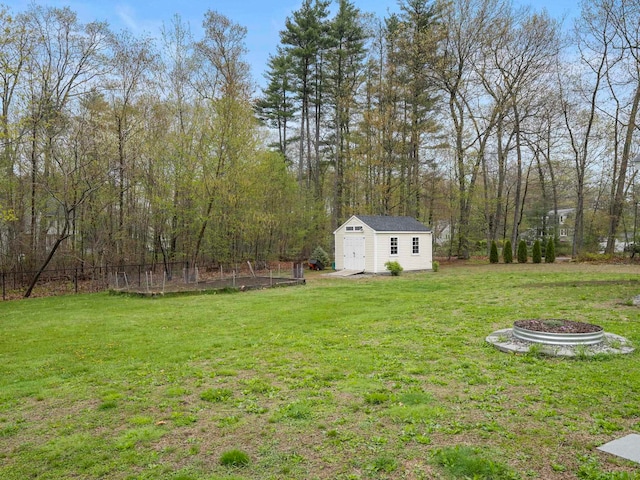 view of yard featuring a wooded view, an outdoor structure, a shed, and fence