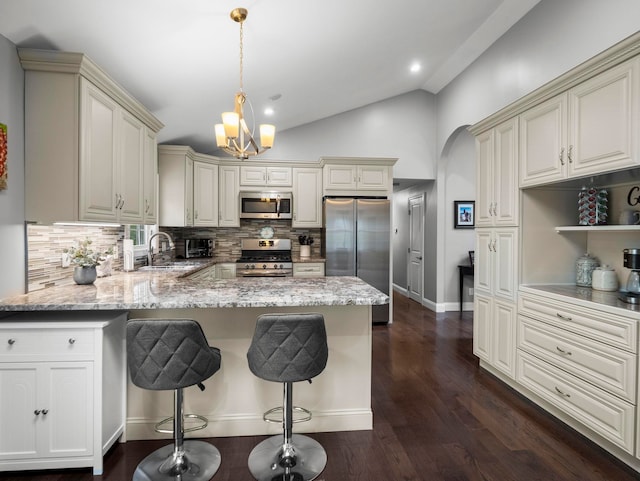 kitchen with a peninsula, stainless steel appliances, cream cabinetry, and decorative backsplash