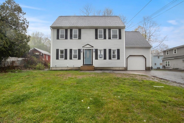 colonial inspired home featuring an attached garage, driveway, a front lawn, roof with shingles, and entry steps