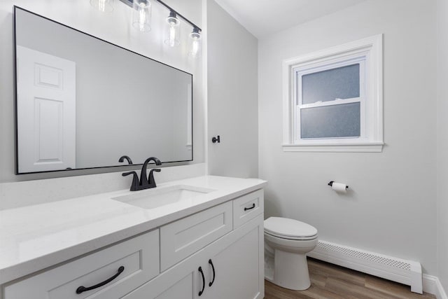 bathroom featuring a baseboard heating unit, baseboards, toilet, vanity, and wood finished floors