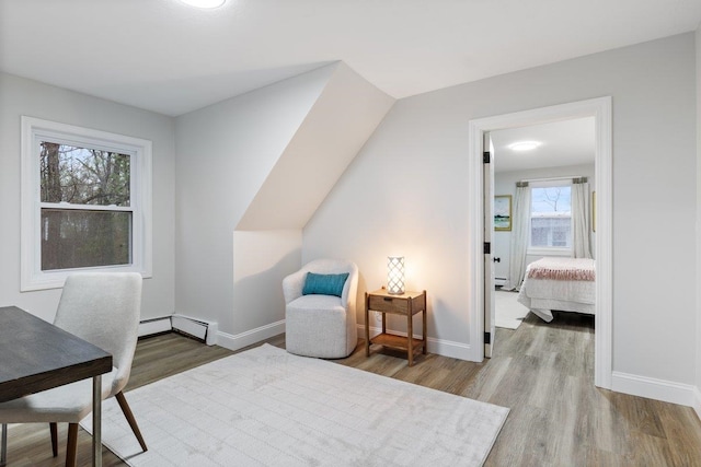 bedroom with baseboards, baseboard heating, and wood finished floors