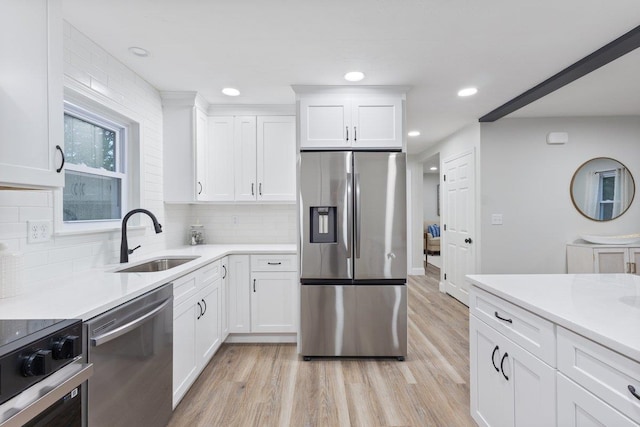kitchen featuring light countertops, stainless steel appliances, light wood-type flooring, and a sink