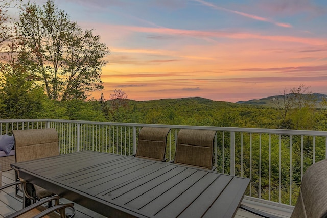 wooden terrace featuring a wooded view and outdoor dining area