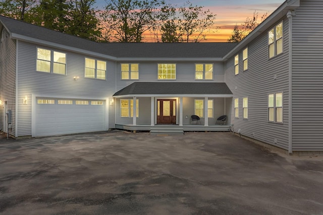 traditional-style home with covered porch, aphalt driveway, and a garage