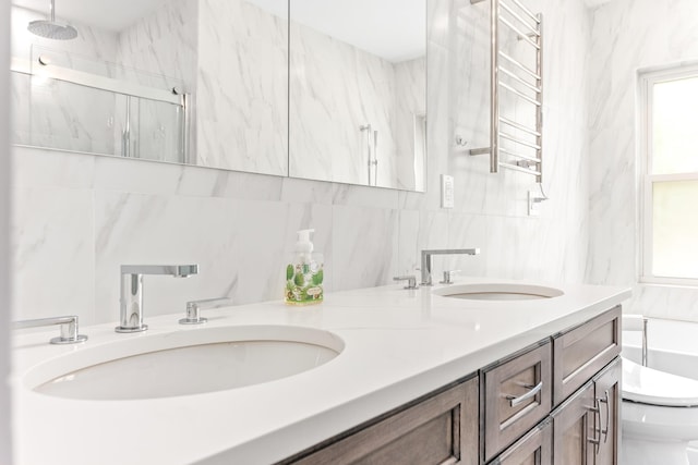 full bath with a marble finish shower, toilet, a sink, and double vanity