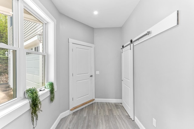 doorway to outside with a barn door, light wood-style flooring, baseboards, and recessed lighting