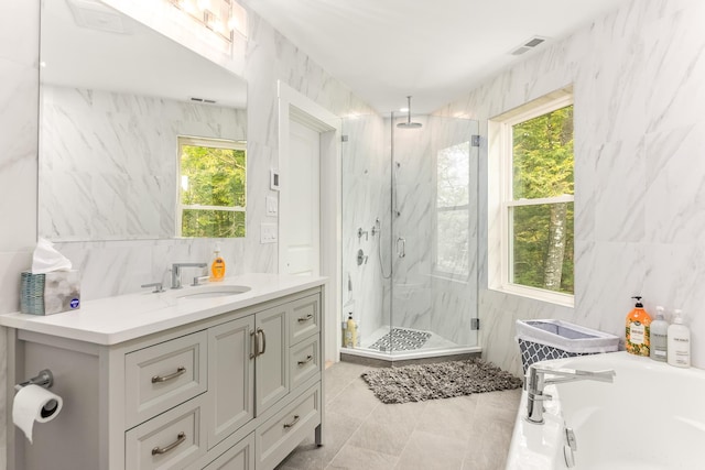 full bath featuring tile walls, vanity, a marble finish shower, visible vents, and a bath