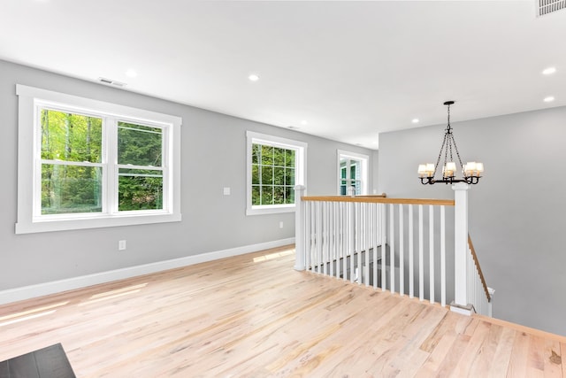 empty room featuring baseboards, a chandelier, visible vents, and wood finished floors