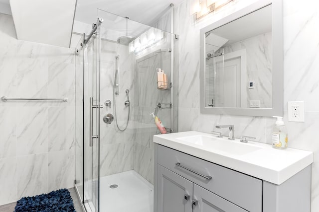 full bathroom with a marble finish shower, tile walls, and vanity
