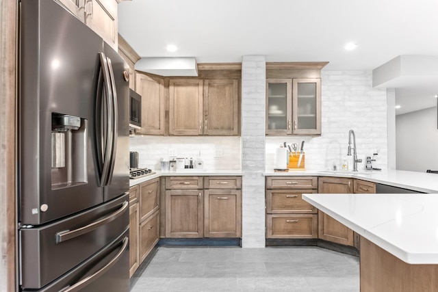 kitchen featuring a sink, a peninsula, tasteful backsplash, and appliances with stainless steel finishes