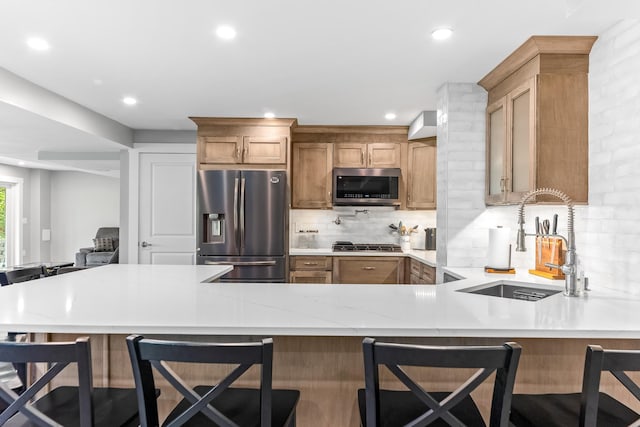 kitchen with a sink, stainless steel appliances, light stone countertops, tasteful backsplash, and recessed lighting