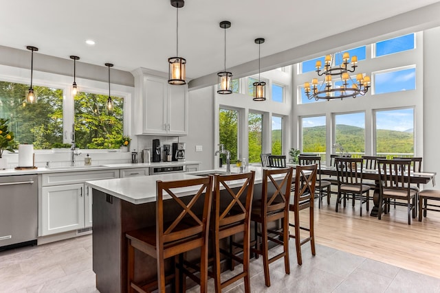 kitchen with stainless steel dishwasher, light countertops, pendant lighting, and a sink