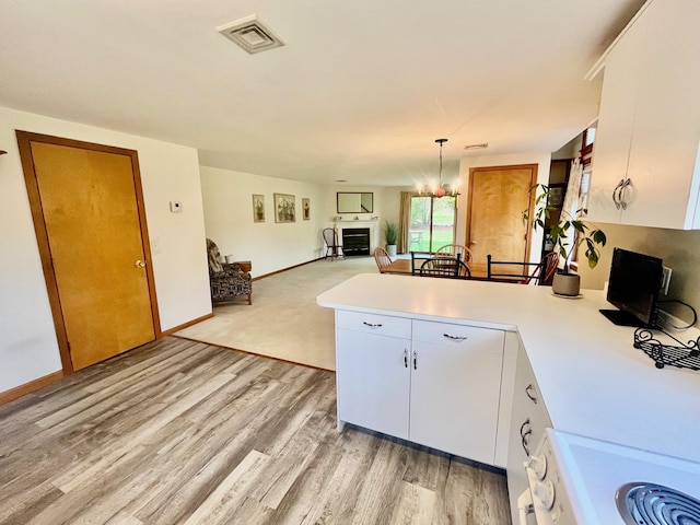 kitchen featuring a notable chandelier, white range with electric stovetop, visible vents, a peninsula, and light countertops
