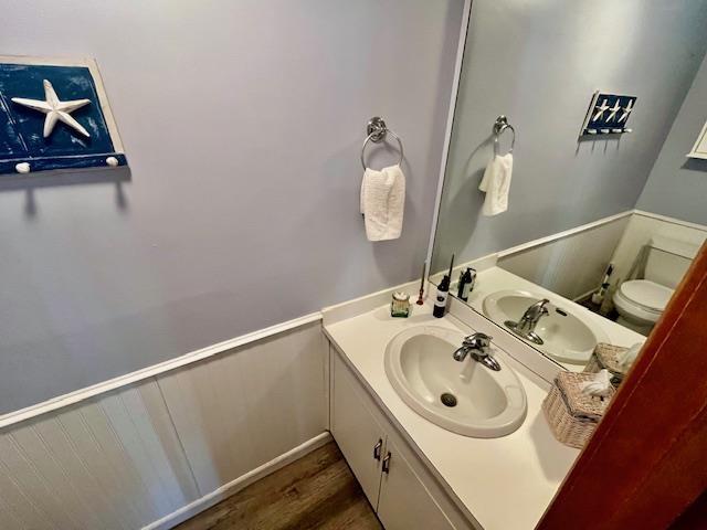 bathroom featuring toilet, wood finished floors, and vanity