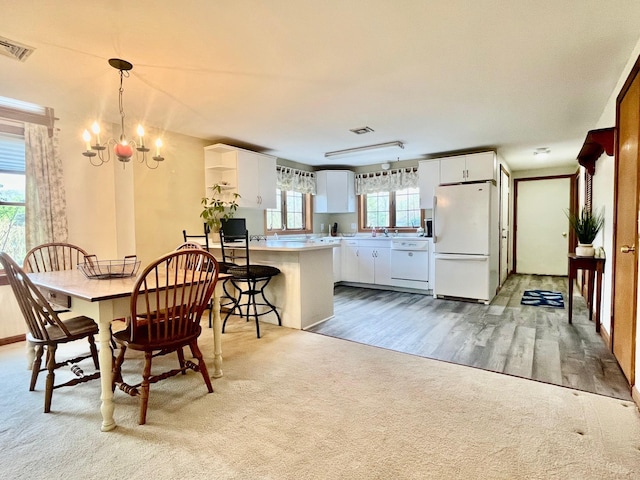 dining area with light wood-type flooring, a chandelier, visible vents, and light colored carpet