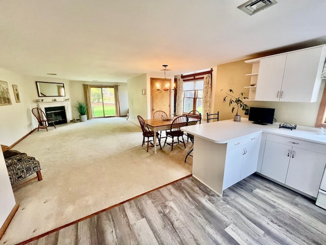 kitchen featuring a peninsula, open shelves, visible vents, light countertops, and white cabinets