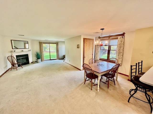 dining space with light carpet, baseboards, a fireplace with flush hearth, and a notable chandelier
