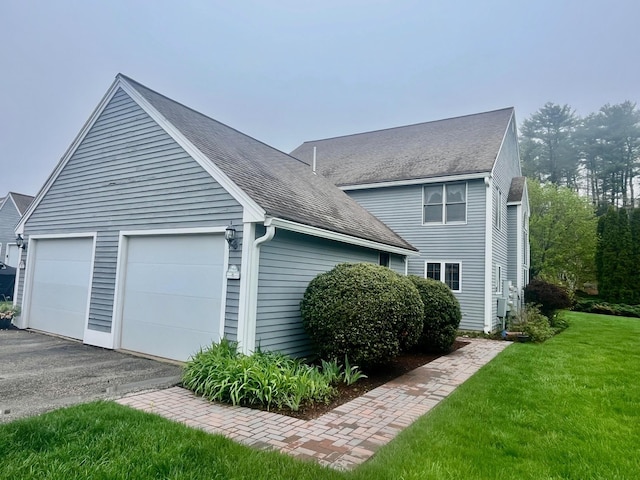 view of front of house featuring a front lawn, roof with shingles, and a garage