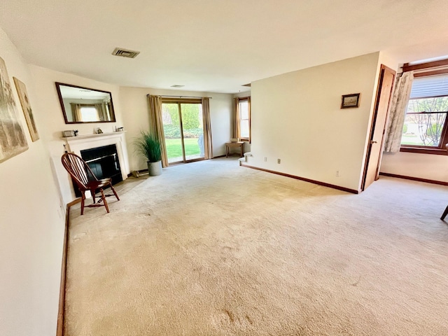unfurnished living room with visible vents, baseboards, a glass covered fireplace, and carpet floors