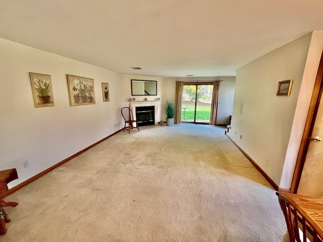 unfurnished living room with light carpet, baseboards, and a glass covered fireplace