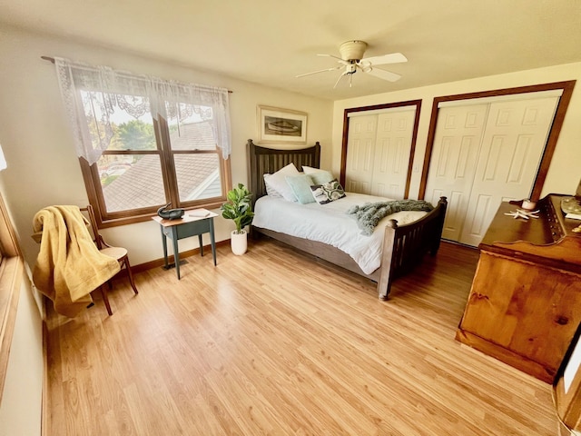 bedroom featuring baseboards, light wood-style flooring, a ceiling fan, and multiple closets