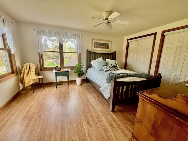 bedroom featuring baseboards, multiple closets, light wood-style flooring, and ceiling fan