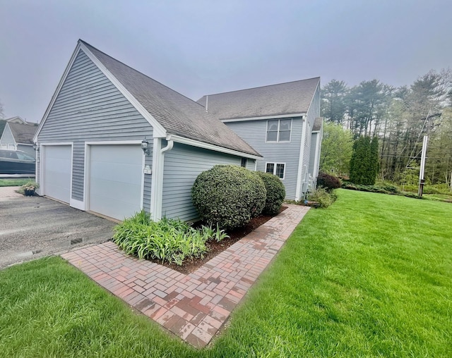 view of property exterior with a yard, roof with shingles, and a garage