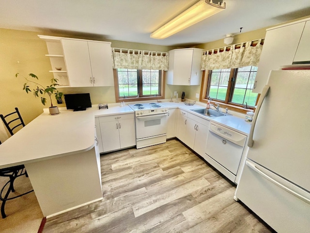 kitchen featuring a sink, a peninsula, white appliances, open shelves, and light countertops